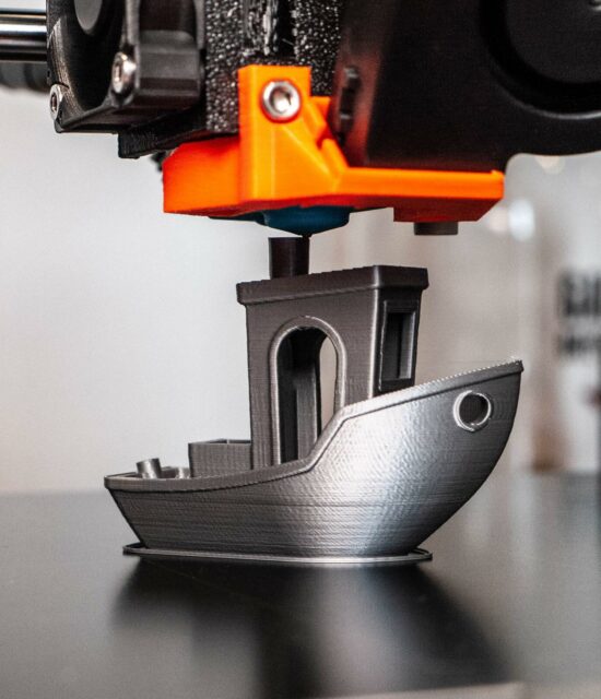 3D printer printing a model boat in silver filament. Taken close