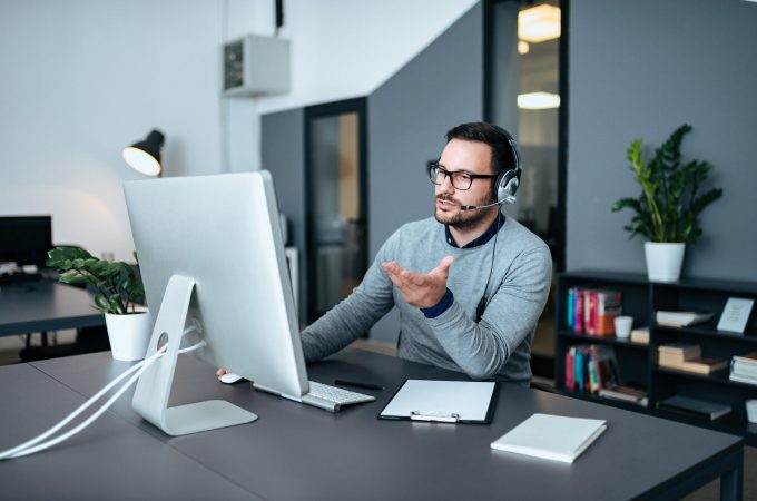 Handsome customer support operator explaining to his customer ho